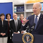 Closer view of Biden at podium. Also in frame is Bertagnolli and three other people.